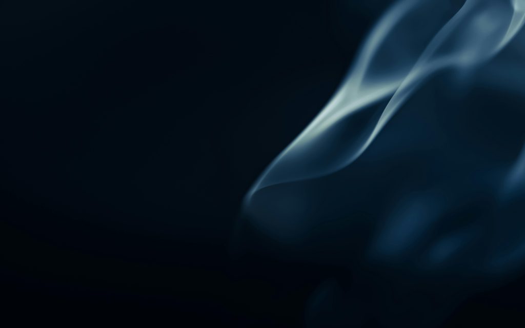 Intriguing abstract image of smoke swirling gracefully in dark blue lighting.