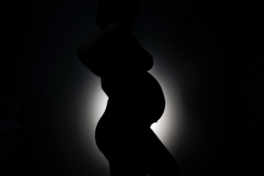 Artistic silhouette of a pregnant woman highlighting maternal beauty against a dark background.